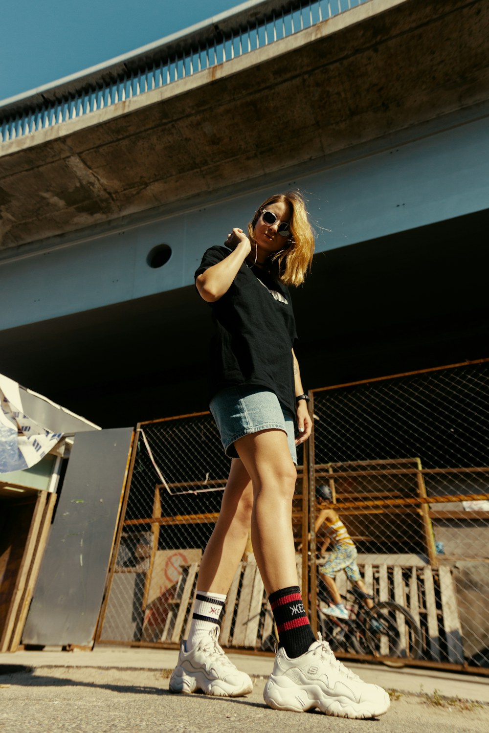 Black T-shirt, denim shorts, tall socks, and chunky white sneakers worn outdoors